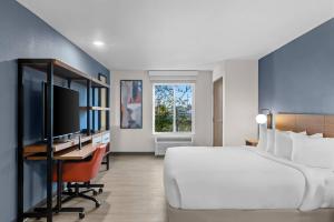 Everhome Suites Bowling Green في بولينغ غرين: غرفة نوم بها سرير ومكتب مع جهاز كمبيوتر +35 صورة