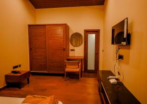 um quarto com uma cama, uma escrivaninha e uma televisão em The Odyssey Coorg em Madikeri