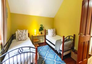 two beds in a room with yellow walls at Kookaburra Retreat - Dog Friendly - Forest View in Gnarabup