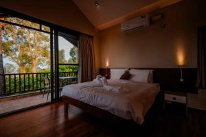 um quarto com uma cama e uma janela grande em The Odyssey Coorg em Madikeri mais 38 fotografias