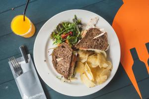 um prato branco com uma sanduíche e batatas fritas e uma salada em Stravinsky Slapen em Hengelo
