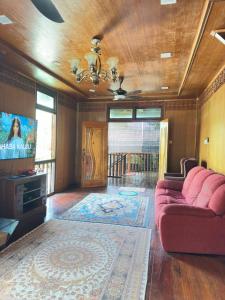a living room with a red couch and a flat screen tv at Indah Desa Homestay in Mantin