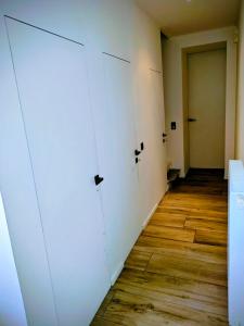 Un pasillo con dos puertas blancas y suelo de madera. en De overkant, en Brujas