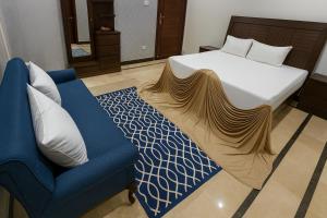 een slaapkamer met een bed en een blauwe bank bij Pinewood Guest House in Islamabad