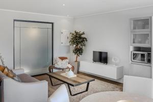 The gallery luxury one bedroom apartment unit 101 في كنيسنا: غرفة معيشة بأثاث أبيض وتلفزيون