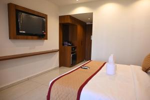 a hotel room with a bed and a tv at Good One Suites Near Manyata Tech Park in Bangalore