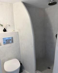 a white bathroom with a toilet and a shower at Fira Heart Studios in Fira