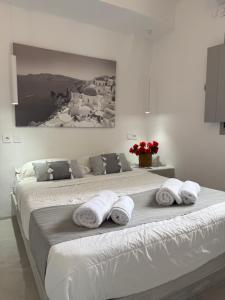 a large white bed with towels on top of it at Fira Heart Studios in Fira