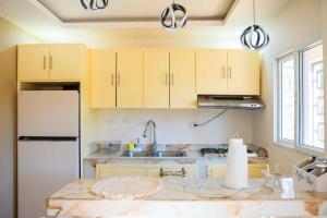 a kitchen with wooden cabinets and a white refrigerator at Summer Bay Luxury Suite - West End - Roatán in Coxen Hole