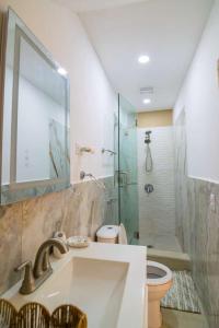 a bathroom with a sink and a toilet and a shower at Summer Bay Luxury Suite - West End - Roatán in Coxen Hole