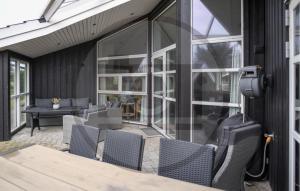 8 Bedroom Lovely Home In Vejers Strand في فايرس ستراند: فناء في الهواء الطلق مع طاولة وكراسي ونوافذ