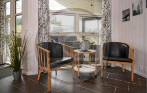 8 Bedroom Lovely Home In Vejers Strand في فايرس ستراند: كرسيين وطاولة في غرفة مع نوافذ