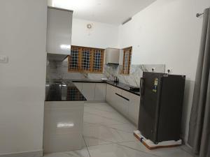 een witte keuken met een zwarte koelkast. bij Aathira Agri Homes in Trichūr