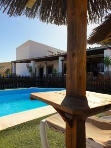 Una mesa de madera junto a una piscina con una casa. en CASA RURAL PRIVADA El ASIENTO LOS GEMELOS, en Pruna