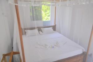 a bed in a white room with a window at Sunny's Hide Out in Talalla