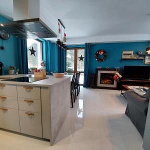 a kitchen and living room with blue walls and a fireplace at Villa Eva & Lilou Pod Rysianką in Żabnica