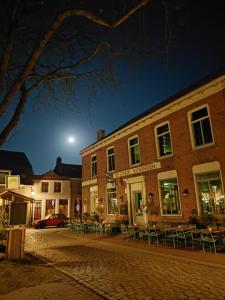 a building with tables and chairs on a street at night at B en B Gewoon Doen Groede in Groede
