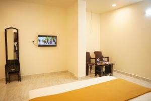 um quarto com uma cama e uma TV na parede em Shri Valli Rooms em Tiruvannāmalai