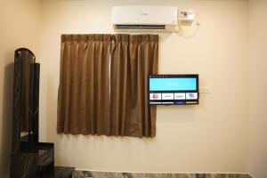 uma televisão pendurada numa parede ao lado de uma janela em Shri Valli Rooms em Tiruvannāmalai