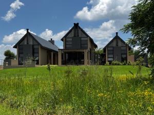 a house with black windows on a green field at VAAL DE GRACE golf estate The SHACK in Parys