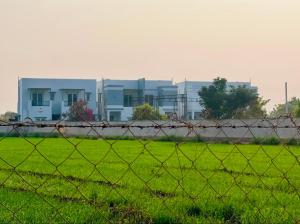 Shree Krushn في بهوي: سور في حقل مع مبنى في الخلف