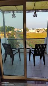 Shree Krushn في بهوي: مقعدان موضوعان على شرفة بها نافذة +صورة واحدة