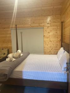 Una cama en una habitación de madera con dos animales de peluche encima. en Cherry hut, en Ajloun