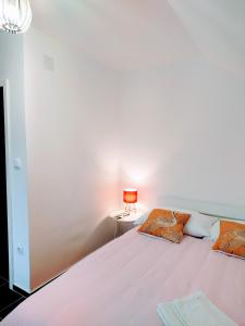 a white bedroom with a bed and a lamp at Tara Mountain House in Bajina Bašta