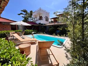a swimming pool with chairs and a house at Vila Uryah in Caraíva