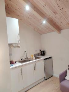 a kitchen with white cabinets and a wooden ceiling at Sky View Cabin in Ardaghy +9 photos
