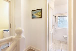 a white bathroom with a toilet and a window at Perle am Watt in List +40 photos