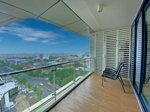 a balcony with a chair and a view of a city at Signature 2BR Apartment ARC100 Vasa Suite Surabaya City Centre with Balcony by Le Ciel Hospitality in Surabaya