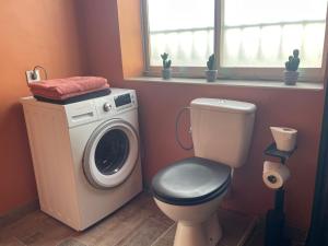 a bathroom with a toilet and a washing machine at Studio Cosy avec déco artisanale unique in Voeuil-et-Giget