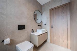 een badkamer met een wit toilet en een spiegel bij Alati Suites - Stegna Beach in Vrachonisída touArchangélou +135 foto's