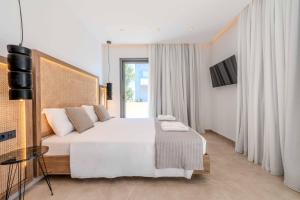 een slaapkamer met een groot wit bed en een televisie bij Alati Suites - Stegna Beach in Vrachonisída touArchangélou