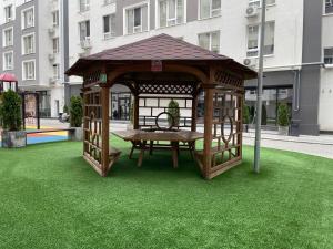 a wooden gazebo with a picnic table in the grass at Modern Apartment in Chişinău