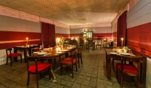 Sukoon - A Wellness Resort, Uttarakhand في Chūharpur: مطعم بطاولات خشبية وكراسي حمراء