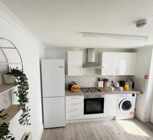 a kitchen with white cabinets and a white refrigerator at The Exmouth Hideaway in Exmouth
