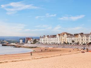 a beach with people sitting on the sand and buildings at The Exmouth Hideaway in Exmouth