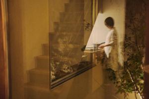 a woman standing in a window looking at a plant at casana KYOTO in Kyoto