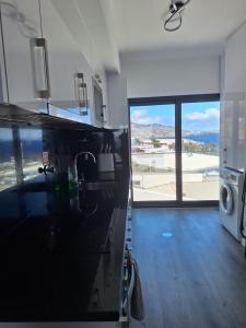 a kitchen with a sink and a large window at Cliff Residence Ocean View in Gaula