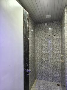 Un baño con ducha con pared de piedra. en Hotel Sky Grand, en Guwahati