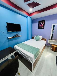 1 dormitorio con 1 cama con paredes azules y TV en Hotel Sky Grand, en Guwahati