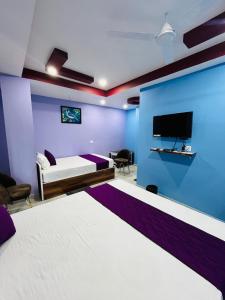 a bedroom with a blue and purple wall at Hotel Sky Grand in Guwahati +11 photos