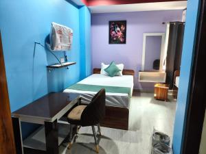 a room with a bed and a desk with a chair at Hotel Sky Grand in Guwahati