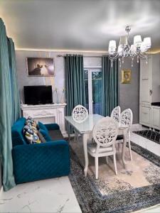 Villa في Gidignitsy: غرفة معيشة مع أريكة زرقاء وطاولة وكراسي