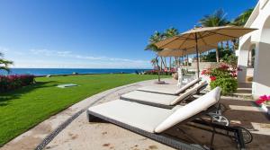 a group of lounge chairs with an umbrella and the ocean at Casa Edwards in San José del Cabo