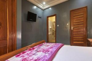 een slaapkamer met een bed en een tv aan de muur bij Tekrour- La case des hotes -Chambre lumineuse proche plage in Mbour +27 foto's