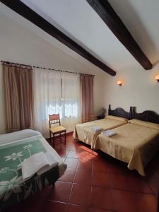 una camera da letto con due letti, una sedia e una finestra di Casa Rural Ivanrey a Ivanrey