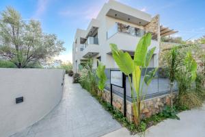 een wit huis met een hek en planten bij Alati Suites - Stegna Beach in Vrachonisída touArchangélou